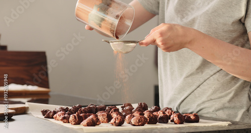 Wallpaper Mural young woman sprinkle cocoa powder on chocolate truffles Torontodigital.ca