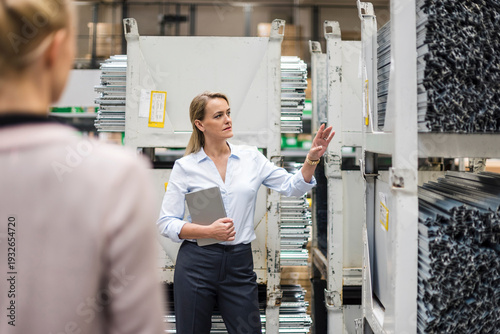 Woman with laptop in high rack warehouse