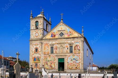 Colorful azulejo-covered church facade with biblical scenes under deep blue sky, Portugal, Válega, 9 October 2025