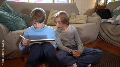 Two brothers drawing and talking together on a tablet