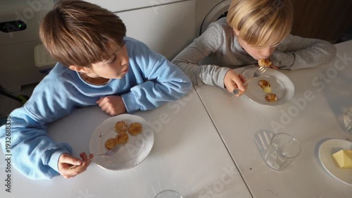 Two brothers eating poffertjes pancakes for breakfast
