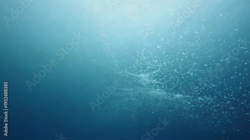 Underwater scene showing continuous bubbles rising through deep blue water, with light filtering from above creating a serene aquatic atmosphere