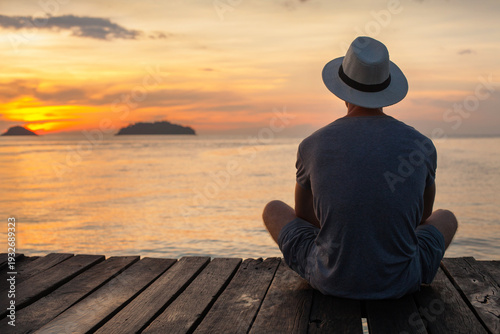 summer holidays travel, man in hat sitting on wooden pier at sunset, quiet moment of relaxation and mindfulness