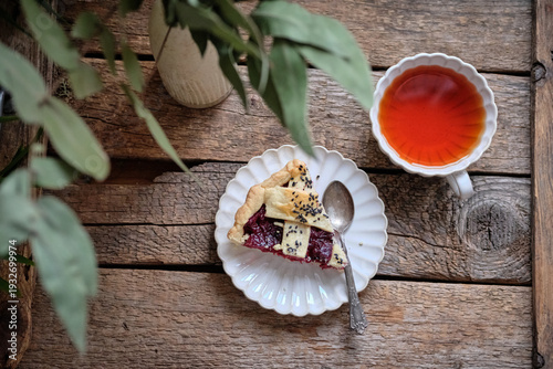 Side view of a cherry pie slice with black sesame and a cup of tea