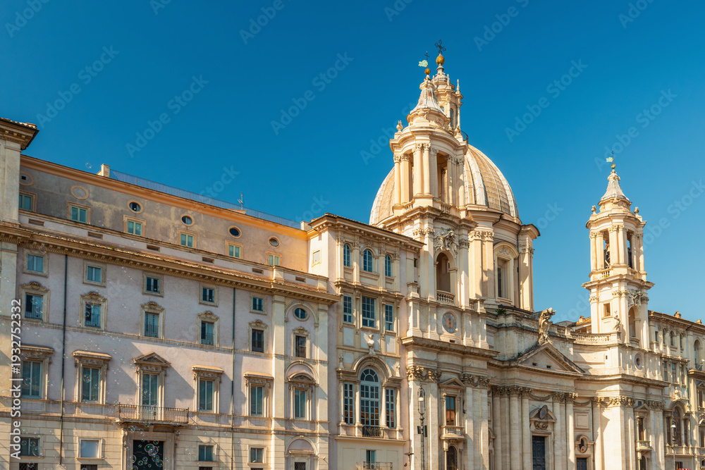 Fototapeta premium View of Sant Agnese in Agone baroque church with grand dome in Piazza Navona against blue sky, Rome city, Italy. Travel and tourism landmark in Europe