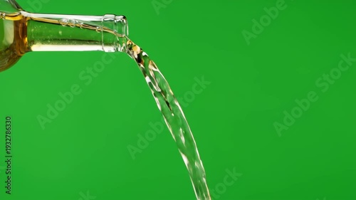 Clear liquid streams from a glass bottle, creating a dynamic flow against a vibrant green screen background, ideal for various projects.