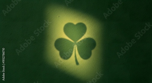 Shadow of a three leaf clover projected onto a textured green wall by a bright light source, symbolizing luck and Irish heritage, ideal for holiday celebrations and spring themes.