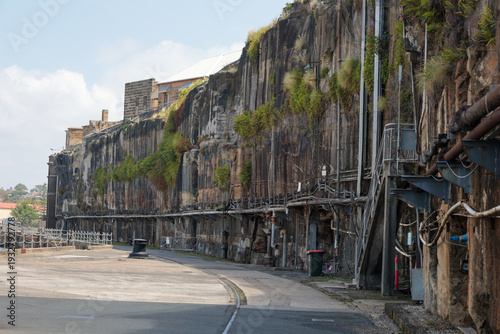 Historic industrial sandstone cliff face with exposed pipes and infrastructure