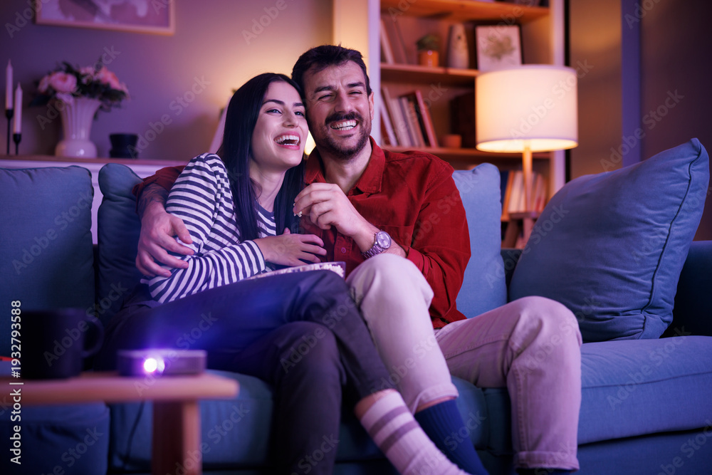 Obraz premium Couple having fun watching TV at home at night