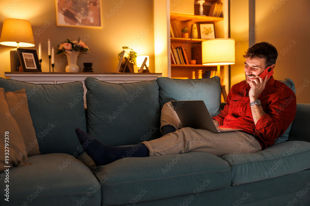 Obraz premium Man having phone conversation using smart phone while relaxing at home at night