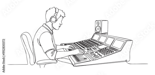 Young male audio engineer wearing headphones working on a professional sound mixing console in a studio environment for music production and broadcast applications