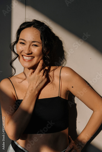 A happy young Asian woman smiles as the sun's rays fall on her. Positive emotions concept