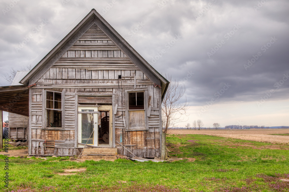 Obraz premium Abandoned Wooden House: An Echo of the Past. A weathered and worn abandoned wooden house in a rural landscape. 