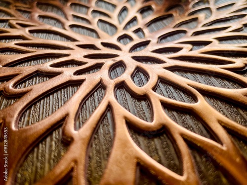 Elegant bronze-colored floral cutout mat with intricate patterns on a dark textured surface