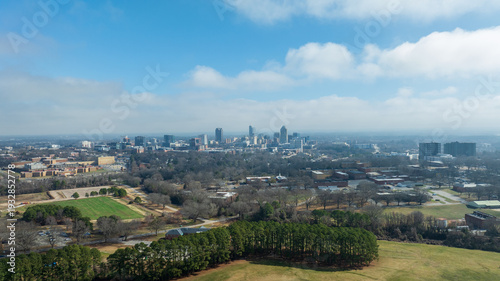 Downtown Raleigh skyline with surrounding residential neighborhoods under clear blue sky.
