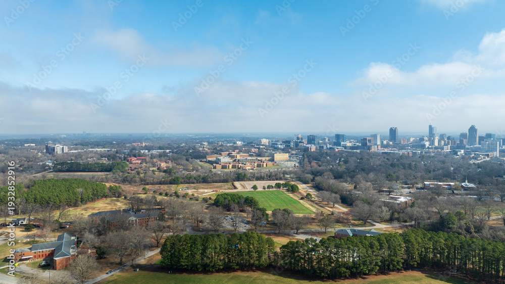 Naklejka premium Downtown Raleigh skyline from Dorothea Dix Park with open fields and trees in foreground.
