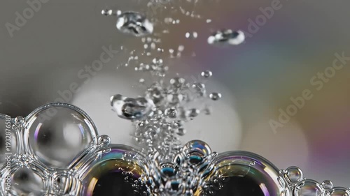 Closeup macro shot of iridescent soap bubbles forming a cluster with water droplets and light reflections abstract background.