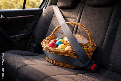 Easter basket with colorful eggs and festive cake secured with a seatbelt on the backseat of a car. A humorous and heartwarming symbol of care and celebration.