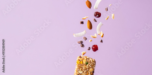 Granola energy bar with falling nuts and dried fruits on pastel background for healthy snack concept. fitness nutrition, energy and muscle building, sports supplement, high protein snack advertising