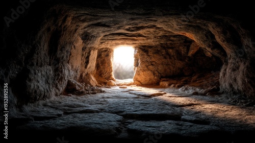 Dawn light shaft in dark rocky cave interior striking stone floor