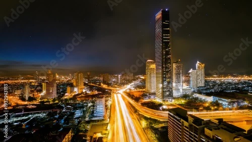 A night aerial view of a vibrant cityscape, showcasing illuminated skyscrapers and highways