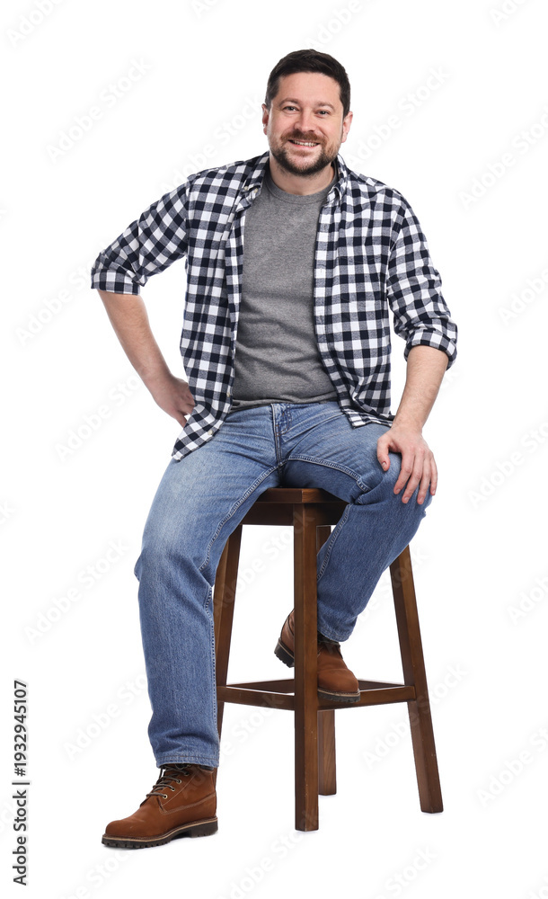 Fototapeta premium Smiling long-haul truck driver in checkered shirt sitting on stool against white background