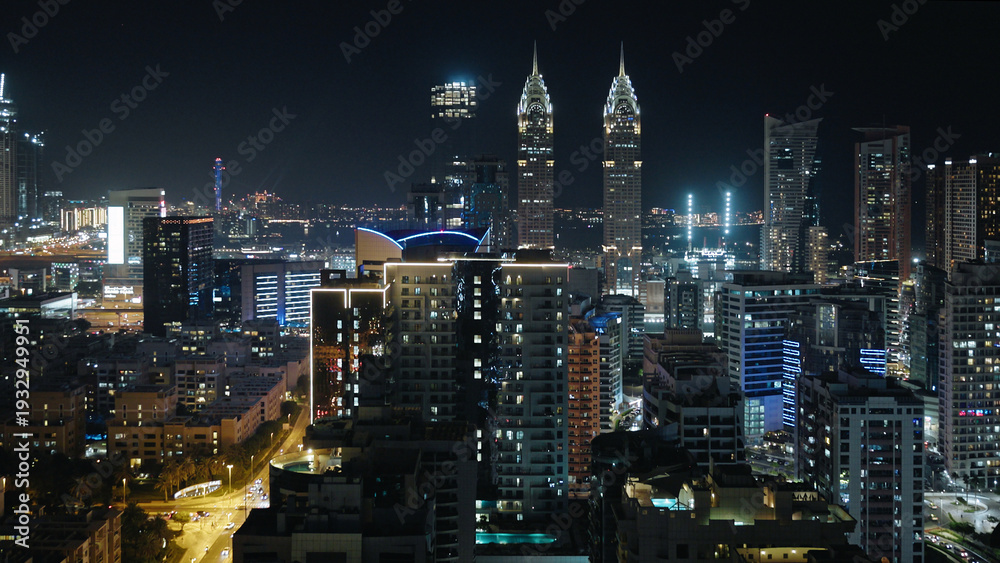 Obraz premium Dubai by night, city skyline with The Business Central Towers, illuminated highways, and modern glass and steel skyscrapers, aerial view.