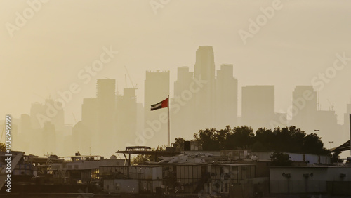 Quadro em tela Dubai City visual contrast, modest run-down houses by the water in the foreground, and downtown skyscrapers in the background
