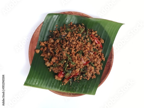 Indonesian stir-fried fermented soybean cake (Oseng Oseng Oncom) with banana leaf and wooden plate isolated on white background. Perfect for culinary, travel, and Asian food culture themes