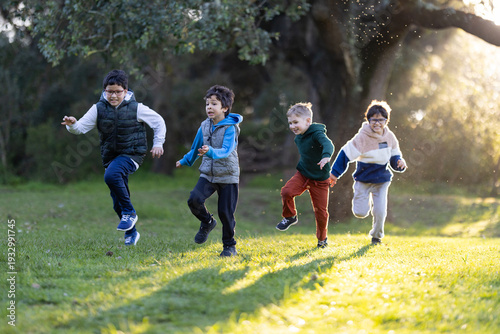 Canvas Print Four young boys running outdoors in golden hour