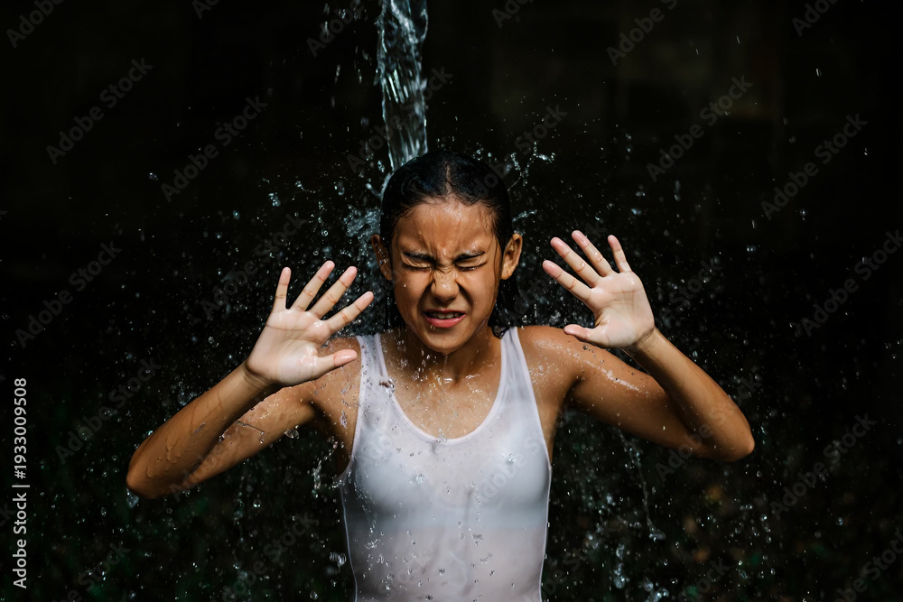 Fototapeta premium Young girl recoils from splashing water in a white tank top child