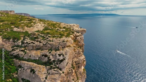 Sanap Cliffs on Gozo island, part of Maltese island. Green fields, rocks and cliffs, sea. boats. Drone view