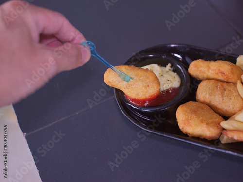 Hand Dipping Crispy Chicken Nugget into Tomato Ketchup