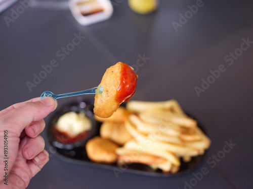 Hand Dipping Crispy Chicken Nugget into Tomato Ketchup