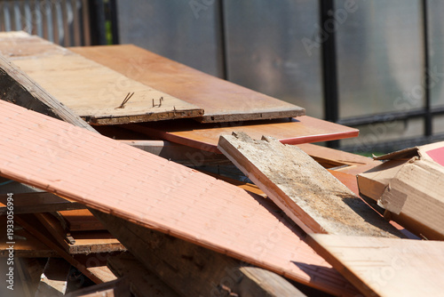 Pile of old wooden planks, discarded furniture parts, and construction debris outdoors.