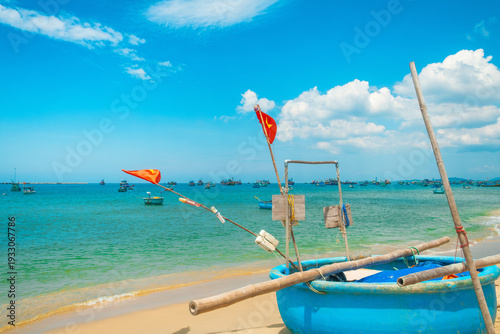 Traditional fishing shoreline with round basket boat and Vietnamese flafs on sandy tropical beach with turquoise water sea on Phu Quoc island, Vietnam. Vietnamese fishing culture