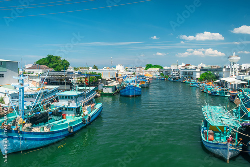 Colorful wooden fishing boats line a narrow harbor channel with tropical waterfront village on Phu Quoc island, Vietnam. Traditional fishing industry in Asia. Sustainable local food supply