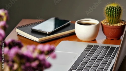 Cozy home office setup with laptop, coffee, and flowers on wooden desk