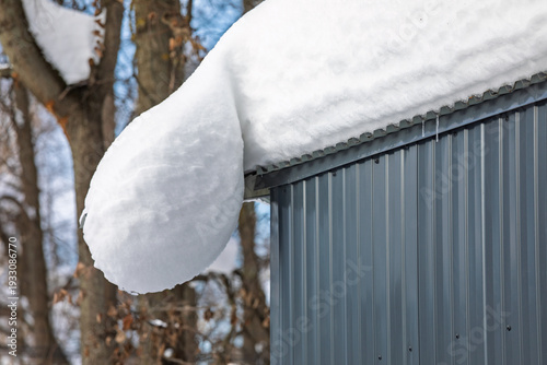Heavy snow overhang on metal shed roof