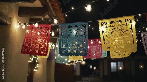 Colorful paper banners with intricate floral hanging under string lights creating festive outdoor