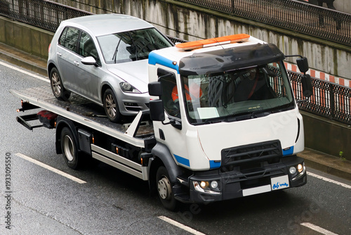 towing  truck car wrecker transporting a broken down car working  in city street