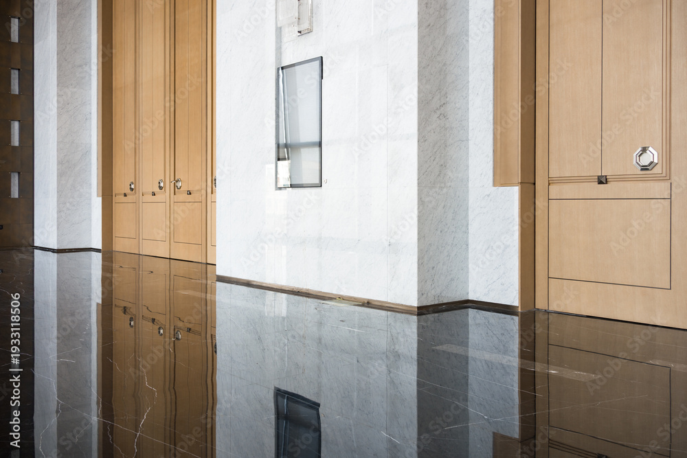 Fototapeta premium Modern office corridor with wooden storage cabinets and polished marble flooring reflecting ambient light