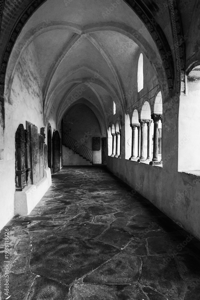 Fototapeta premium Historic cloister corridor with vaulted arches and frescoes in black and white