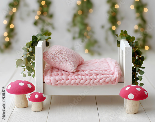 White wooden newborn baby bed, pink chunky knit blanket and pillow, red polka dot toadstools, eucalyptus, bokeh fairy lights, newborn baby photography backdrop.