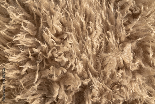 Close-up of beige faux fur texture — soft synthetic wool with curly pile, detailed high-resolution textile background