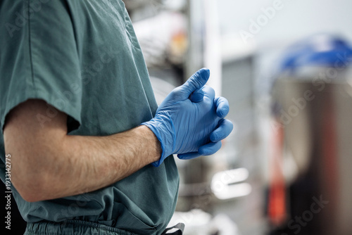 Foto Male healthcare professional in green scrubs wearing blue gloves stands with han