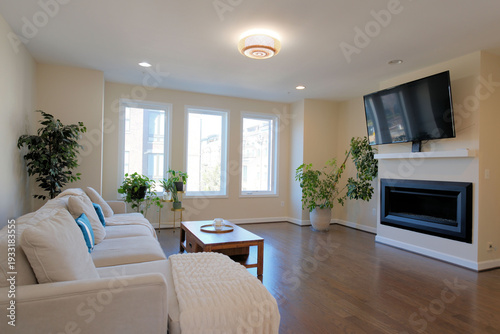 Empty home living room interior featuring a sectional sofa, wood coffee table, fireplace, and large panel television