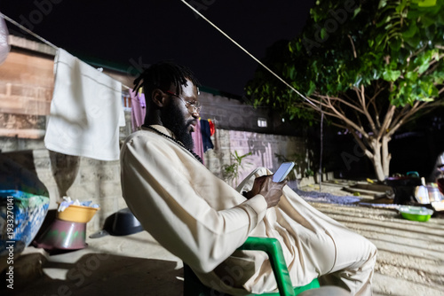African man using smartphone connecting globally at night
