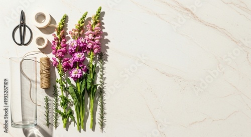floral arrangement with pink flowers and craft materials on white marble surface