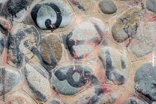 Abstract street art on cobblestone wall with blue, pink and white brushstrokes.